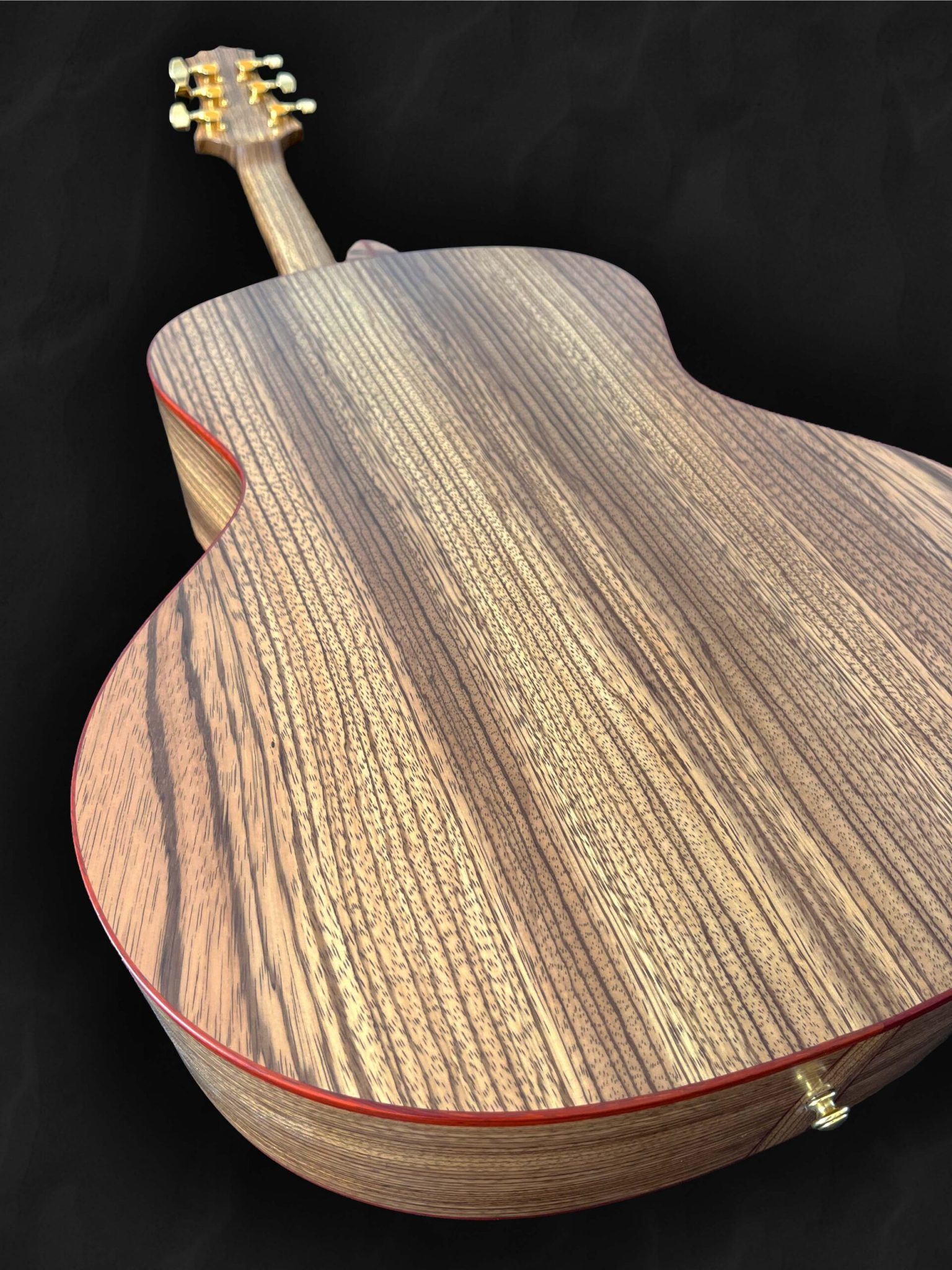 Guitare acoustique jumbo avec ouverture sur le côté, orientée vers le musicien en bois clair épicéa du Jura, Zebrano et liseré rouge